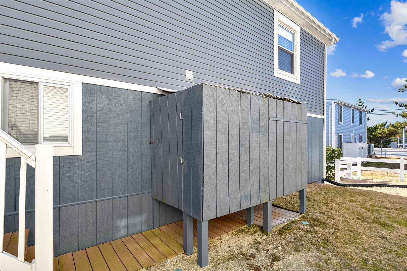 Modern two-story beach rental features a private enclosed outdoor shower and deck area—perfect for rinsing off after a day by the water.