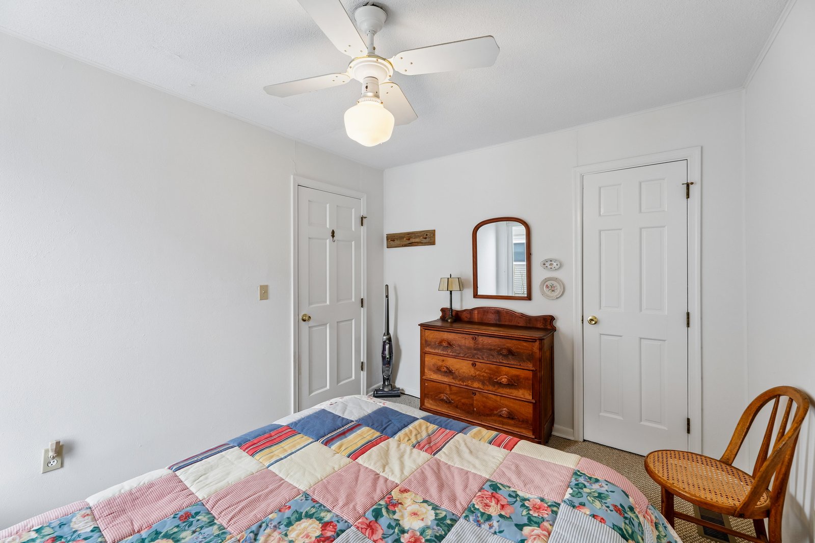 Unwind in this cozy bedroom with classic charm, featuring a handsome wood dresser, vintage mirror, and a colorful patchwork quilt for a homey, comfortable stay.