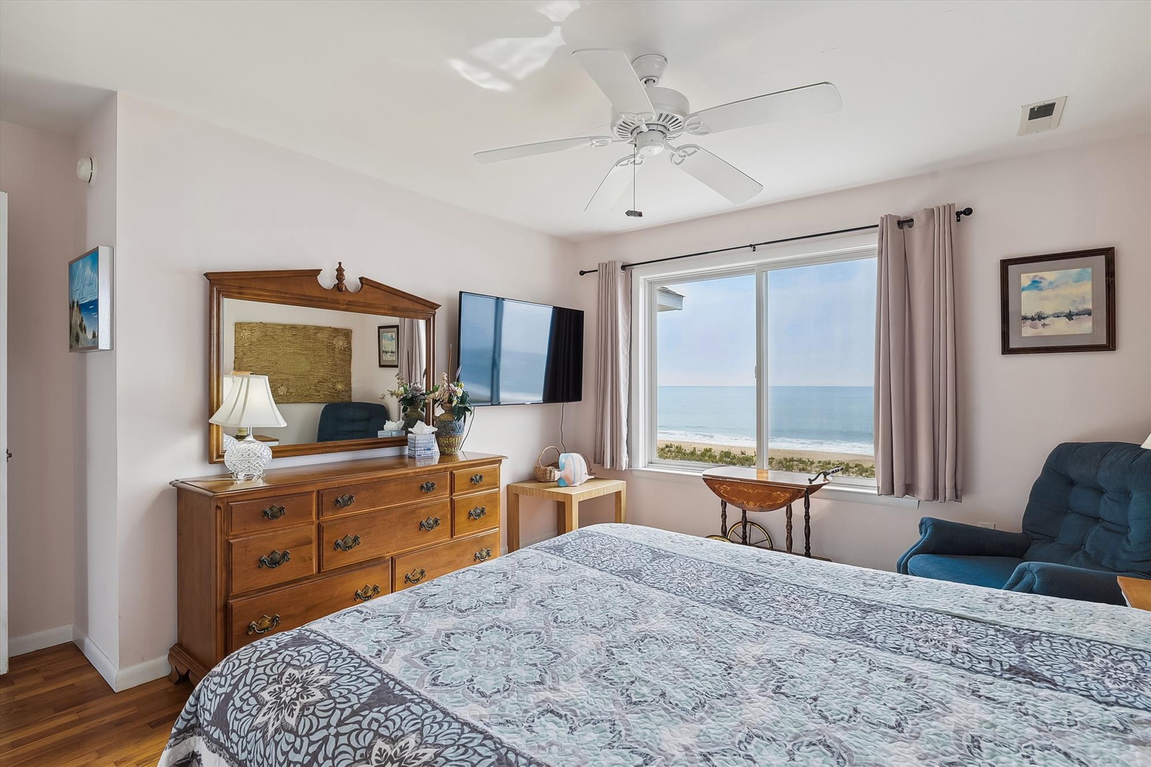 Wake up to stunning oceanfront views from your comfortable bedroom, where a plush bed, ceiling fan, and coastal breeze create the perfect retreat for your beach getaway.