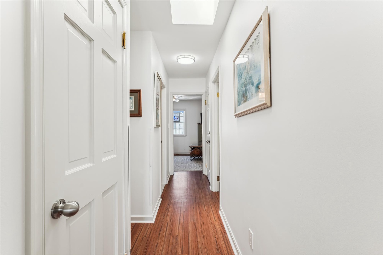 Step into your welcoming hallway, where warm hardwood floors and natural light from above guide you to comfortable living spaces beyond.