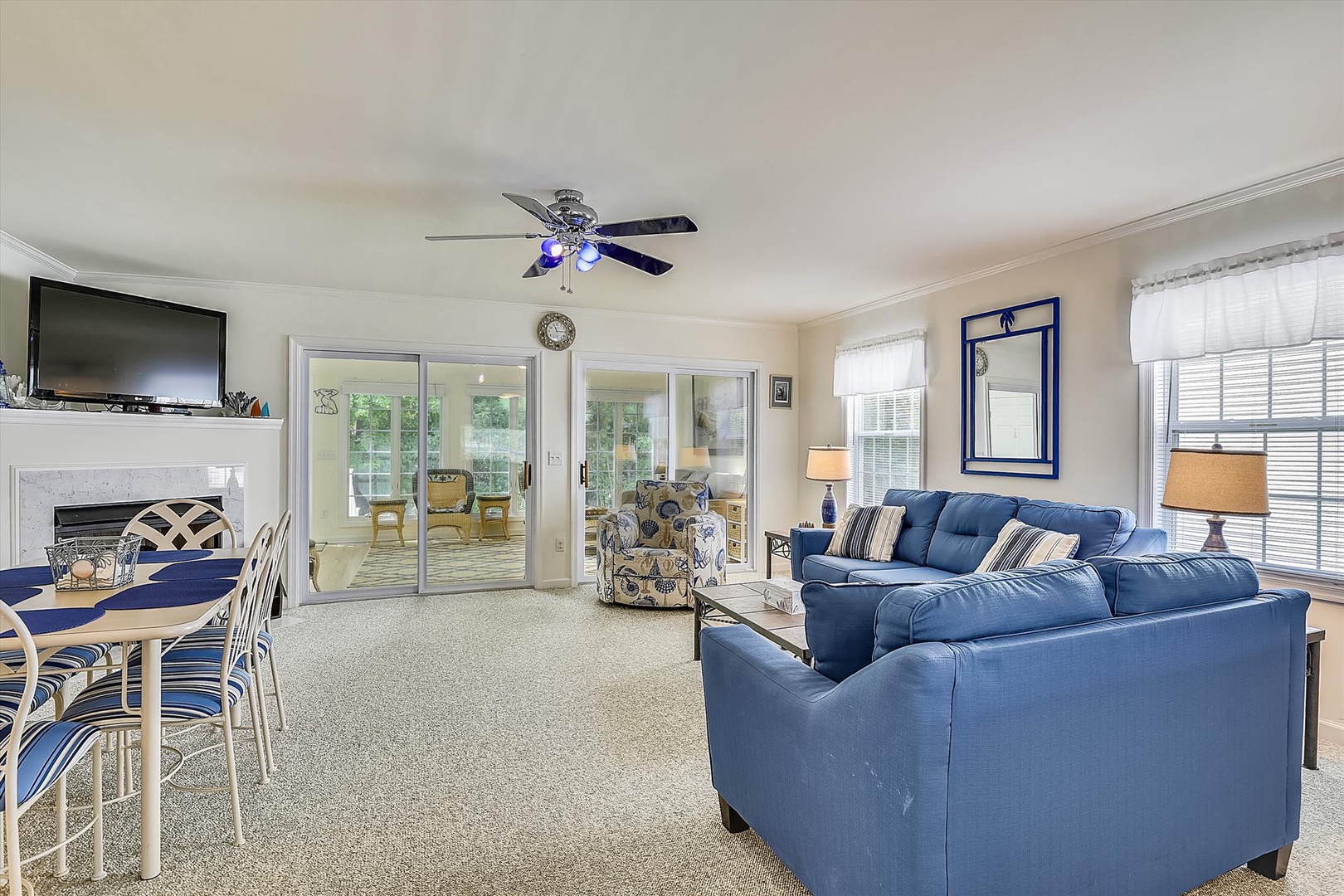 Unwind in your bright living space with plush blue seating, coastal touches, and doors opening to your screened porch—perfect for morning coffee or evening relaxation.