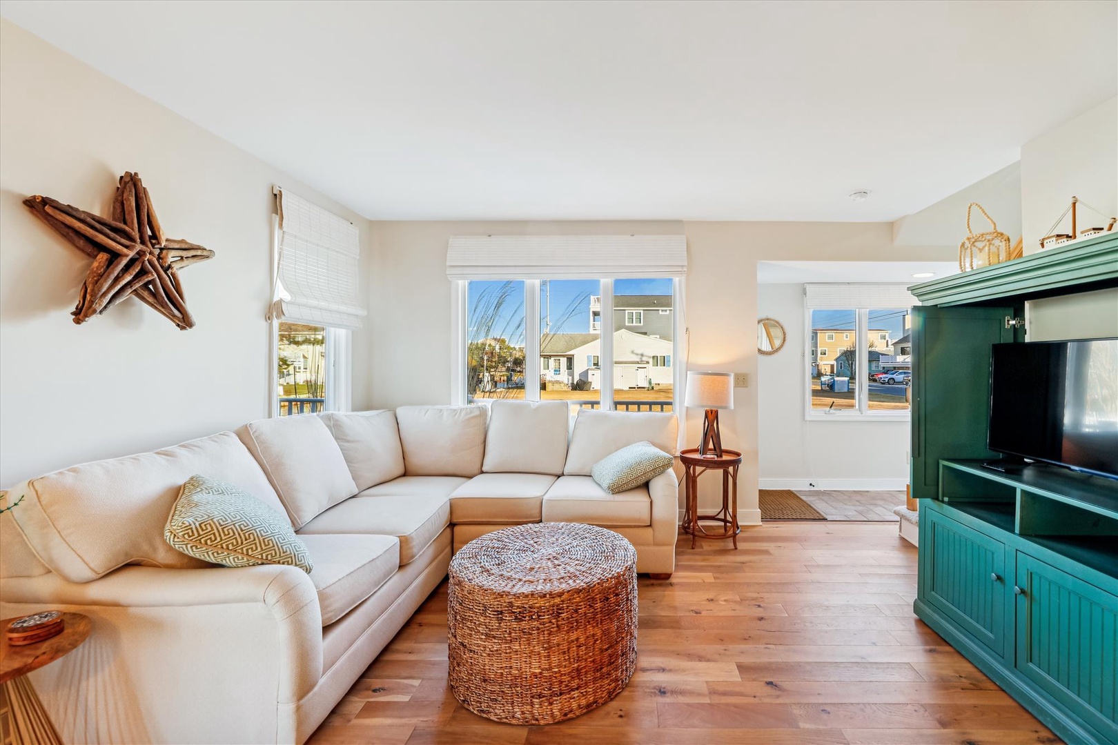 Relax in this bright coastal living room with plush sectional seating, charming nautical touches, and warm hardwood floors beneath your feet.