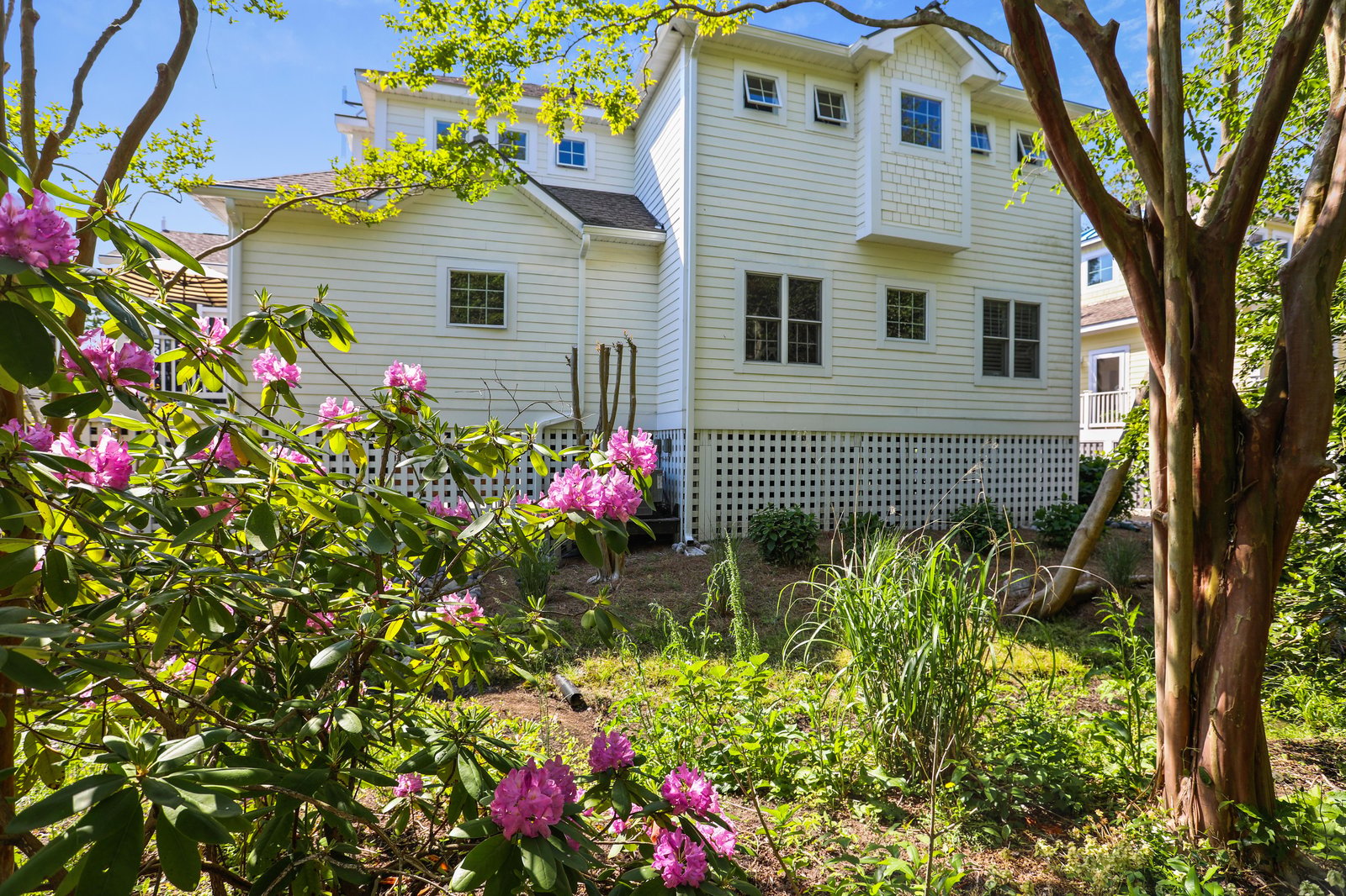 Charming property framed by blooming rhododendrons and mature trees. Spring blossoms and lush greenery surround this peaceful retreat.