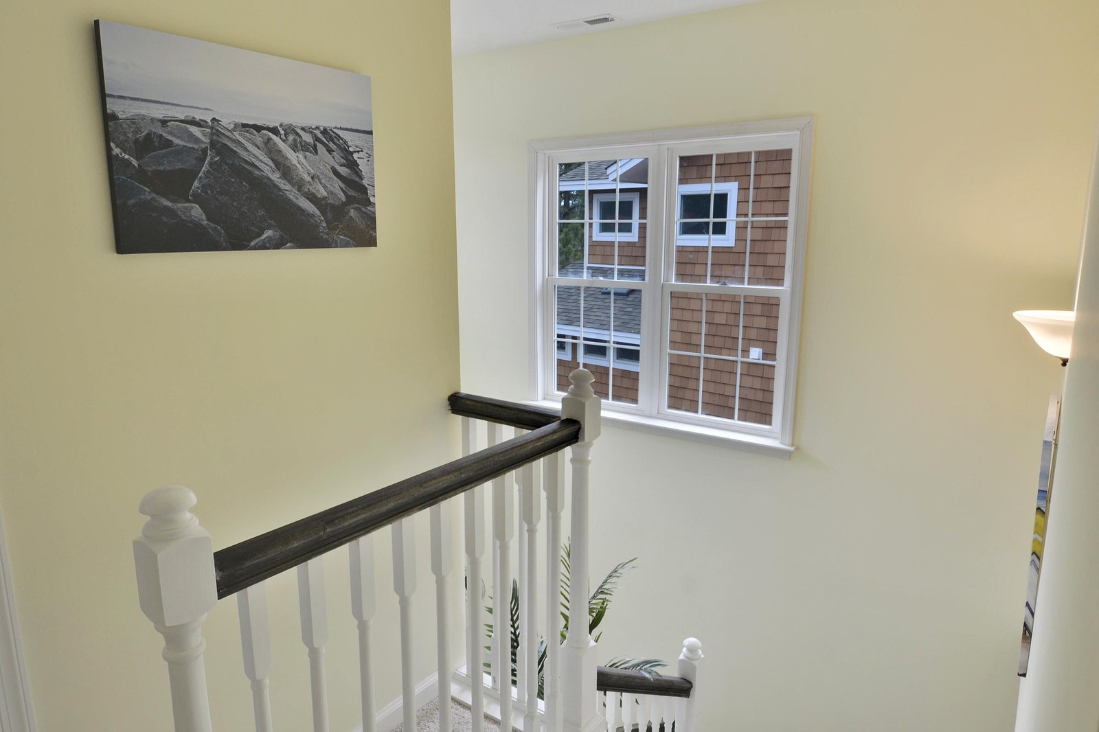 Bright, airy stairwell with sunny yellow walls and white railings leads you through the home, framed by soft natural light.