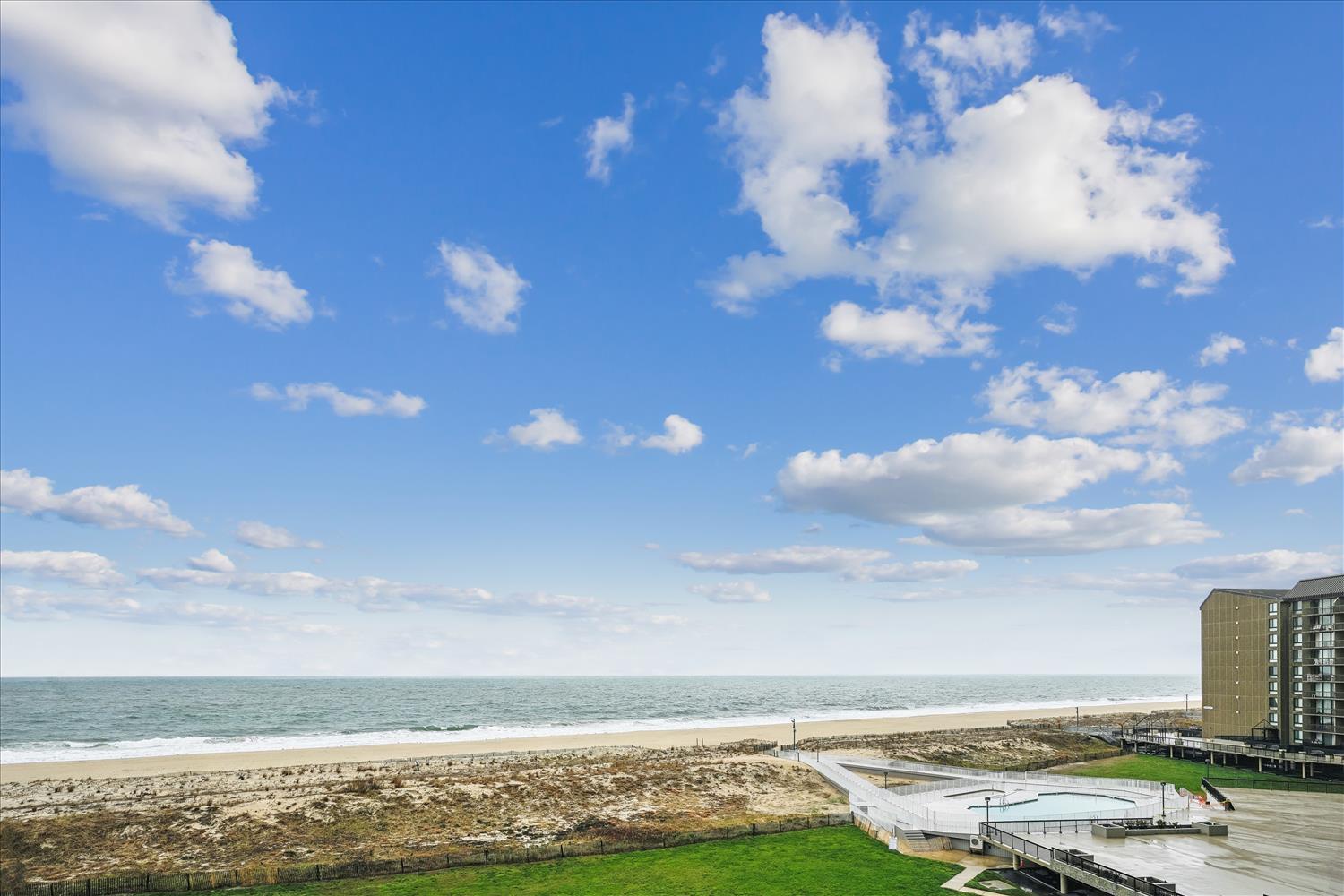 Beachfront property overlooking sandy shores and ocean waves, with nearby coastal facilities offering direct access to seaside relaxation and water activities.