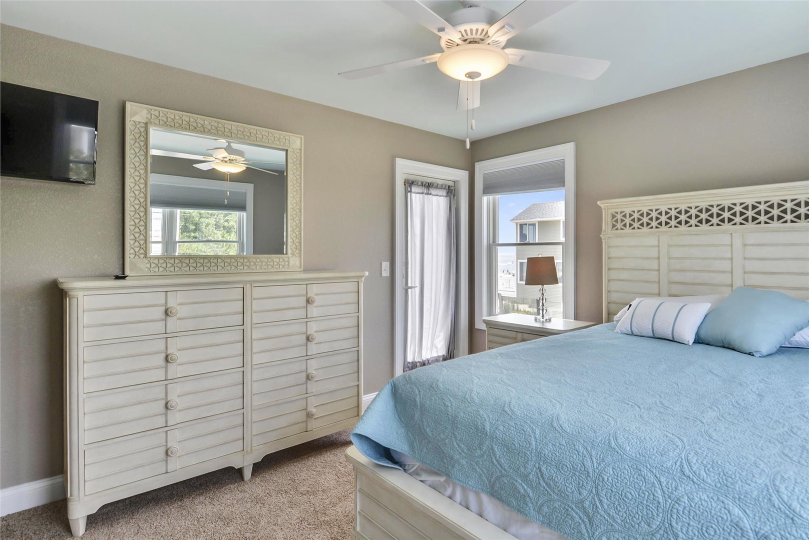 Drift off in your serene coastal-inspired bedroom, complete with soft lighting, calming blue bedding, and breezy ceiling fan overhead for ultimate relaxation.