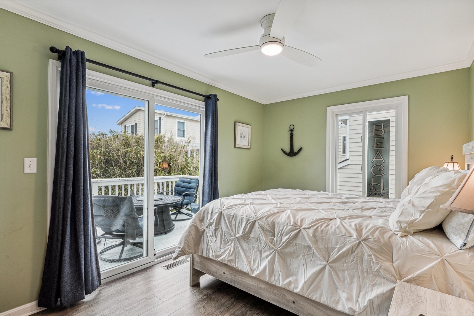 Wake up in your coastal retreat, where soft green walls and a private balcony invite you to embrace the gentle breezes and coastal charm just beyond your door.