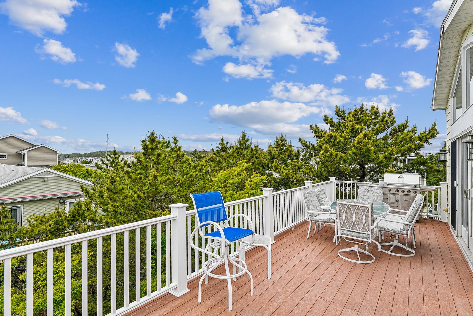 Step out onto your private deck with comfortable seating and a built-in grill, perfect for savoring sunny mornings or peaceful evenings surrounded by lush treetops and open sky.