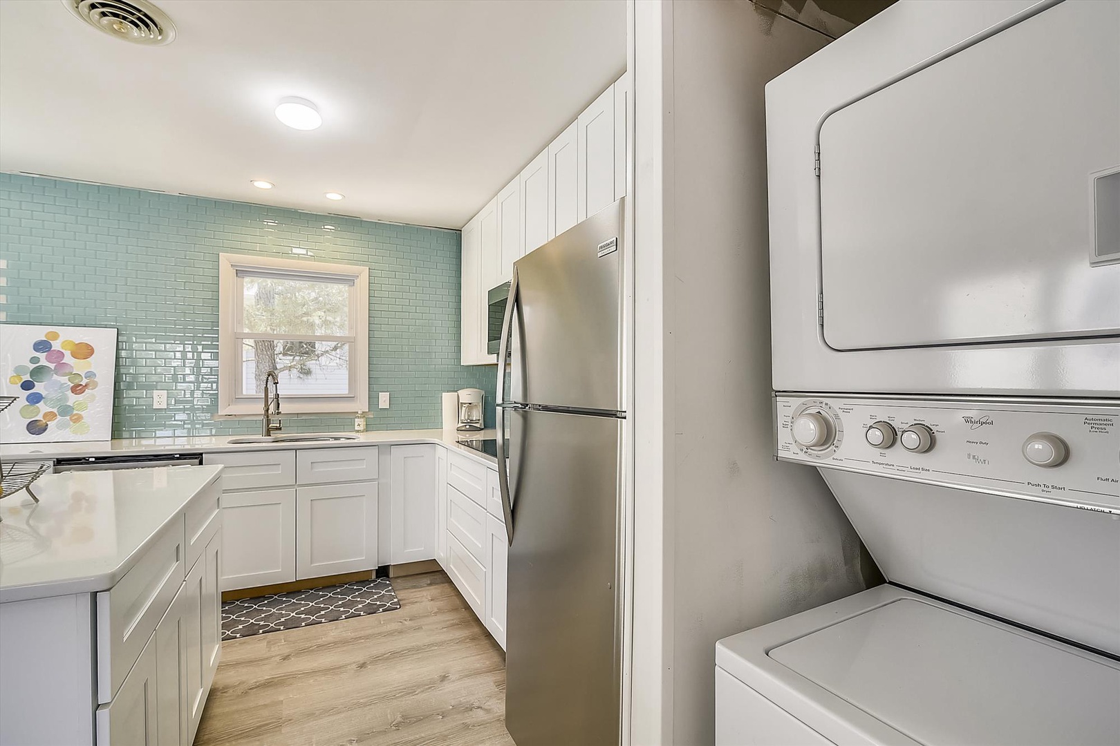 Your bright, fully equipped kitchen features modern appliances and coastal charm with its turquoise tile backsplash. The convenient in-unit washer and dryer make your stay even easier.