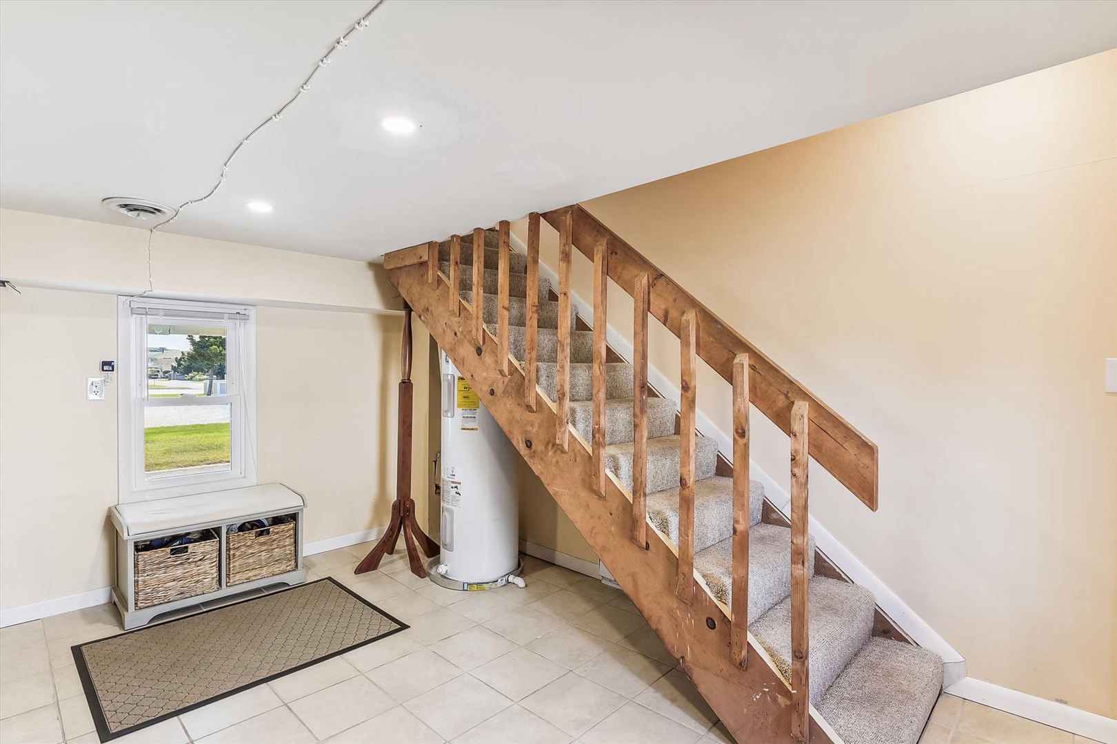 Step inside your welcoming entryway with warm, sun-lit tones and a charming wooden staircase that invites you to explore your spacious retreat.