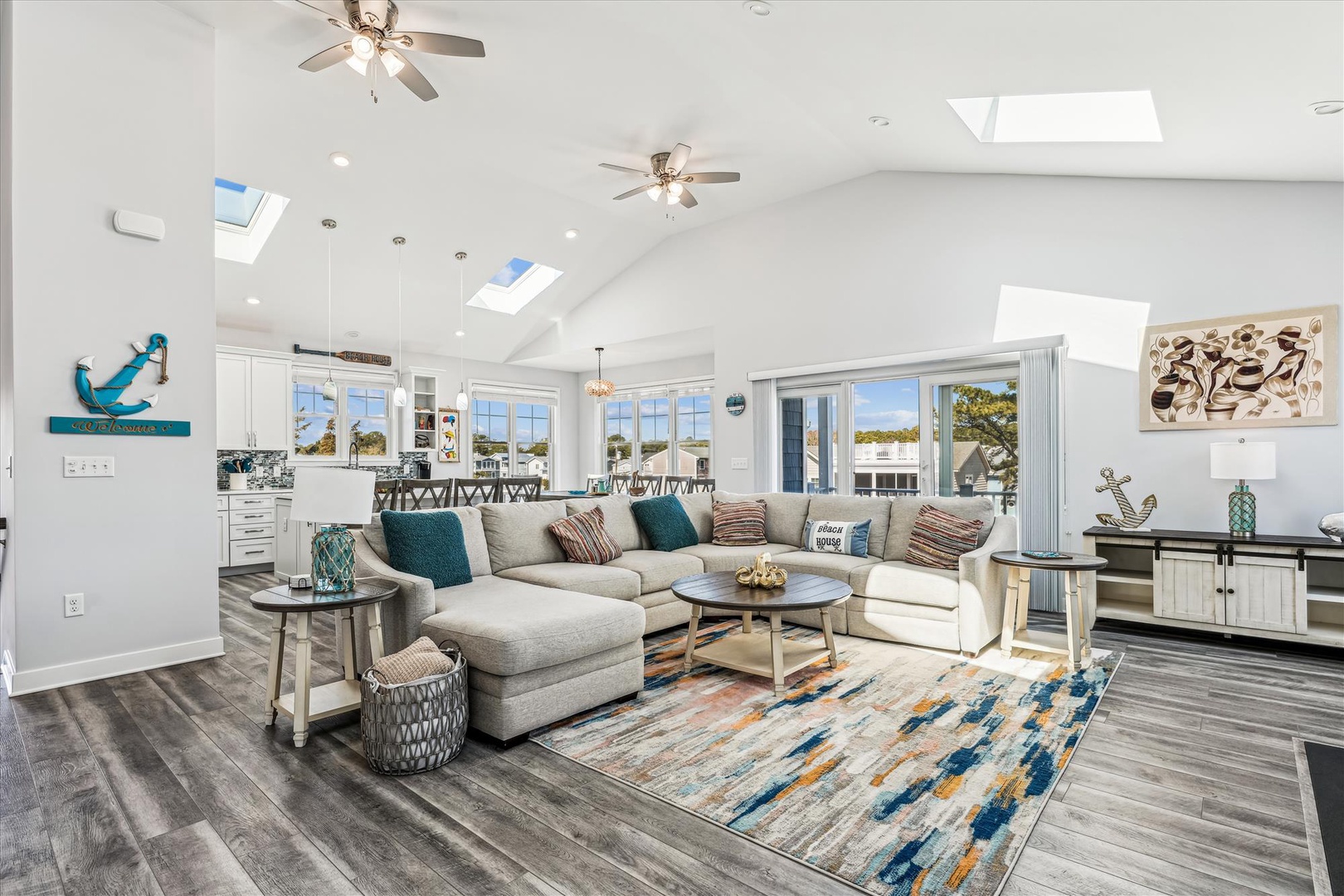 Sink into plush sofas beneath soaring vaulted ceilings with skylights flooding natural light. Your open-concept retreat blends coastal charm with modern comfort—perfect for gathering and unwinding.