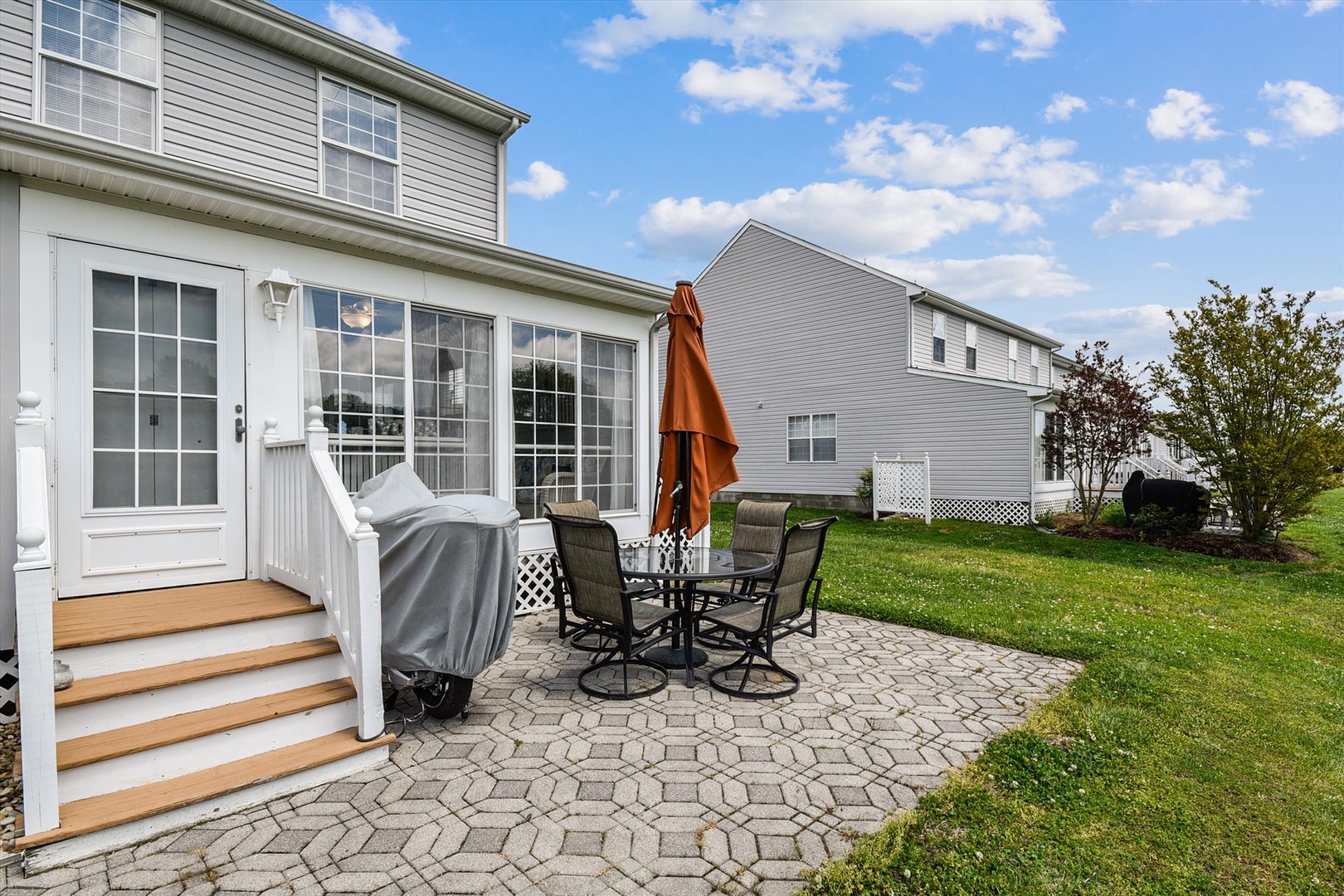 Private backyard patio with outdoor seating, BBQ area, and spacious lawn—ideal for relaxing or entertaining beneath open skies.
