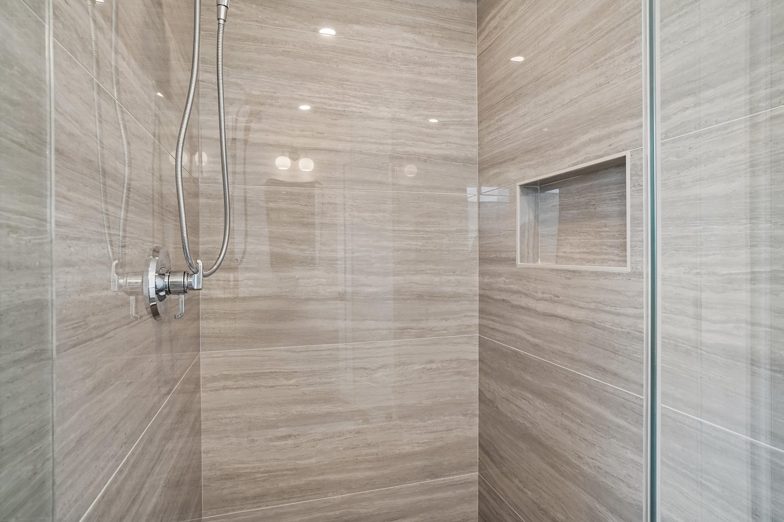 Step into your spacious walk-in shower, where sleek gray tile and chrome fixtures create a modern spa-like retreat. The built-in niche keeps your essentials within reach for an effortless start to your day.