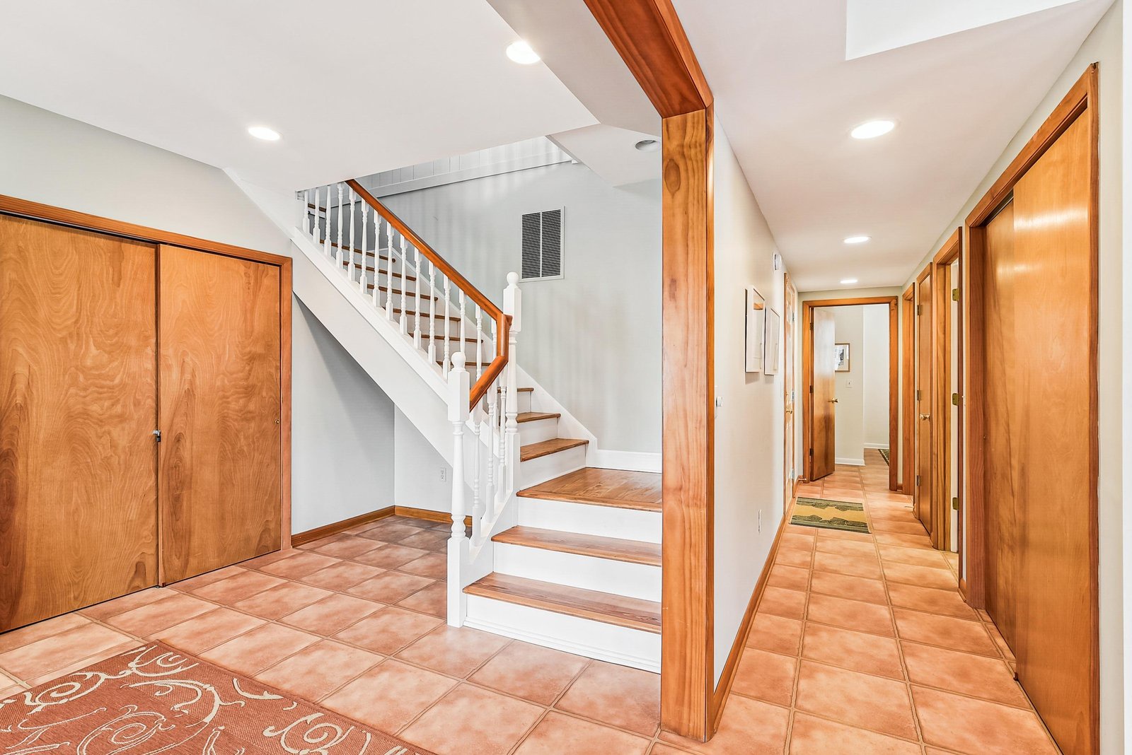 Step into a bright, welcoming home with warm wood tones and terracotta tile floors that guide you through spacious rooms and up the elegant staircase to your private retreat.