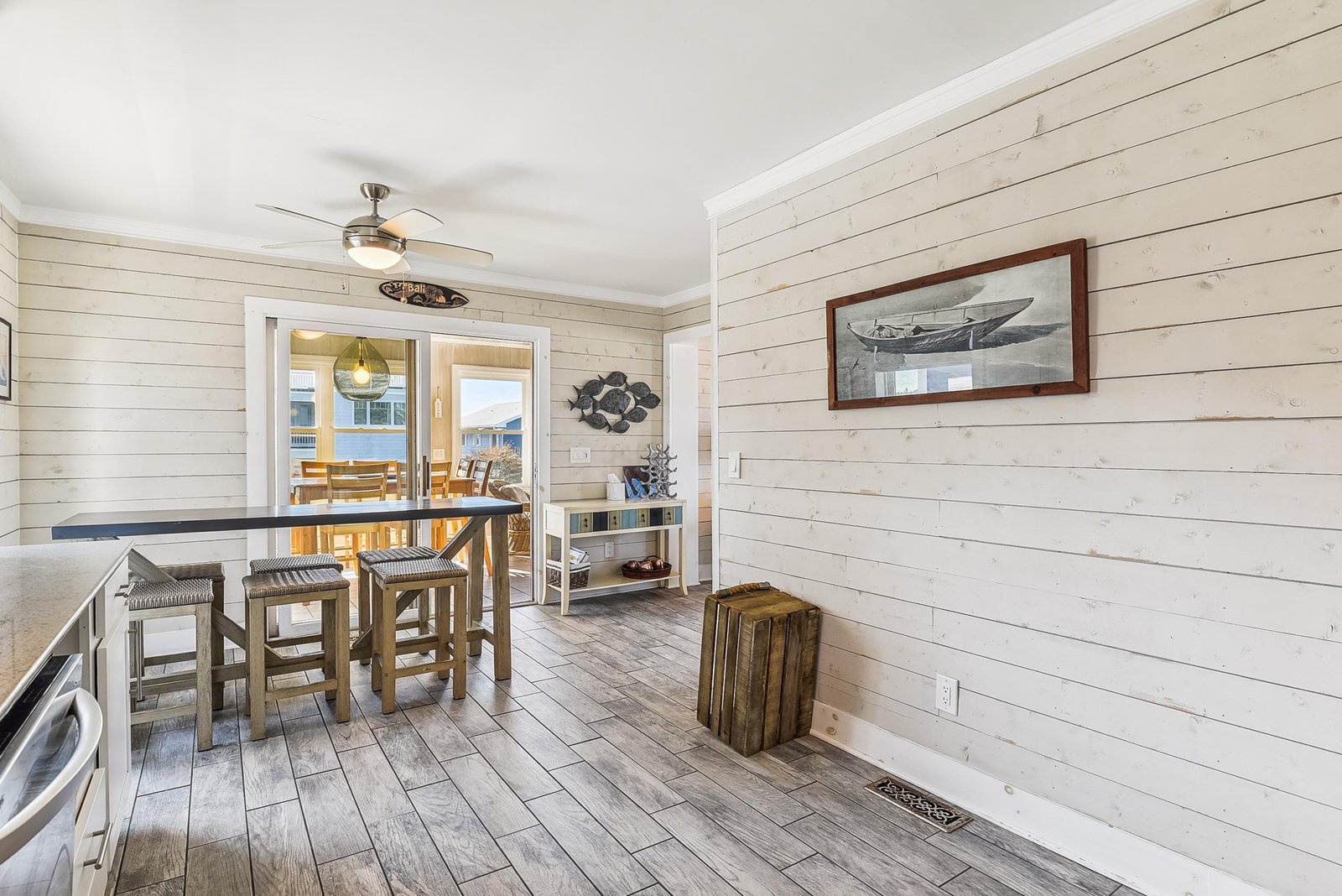 Step into your coastal-inspired retreat where shiplap walls and weathered wood floors create a breezy, relaxed vibe. The high-top table is perfect for morning coffee, and through those doors, a private deck awaits your arrival.