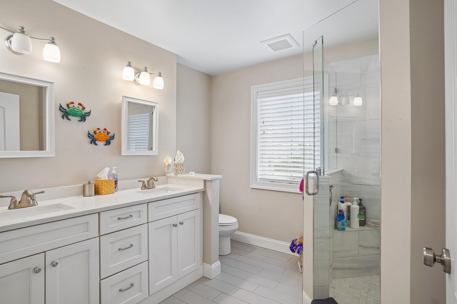 Your bright, spacious bathroom features a double vanity for convenience, a walk-in glass shower, and playful coastal touches that create a welcoming, beach-inspired retreat.