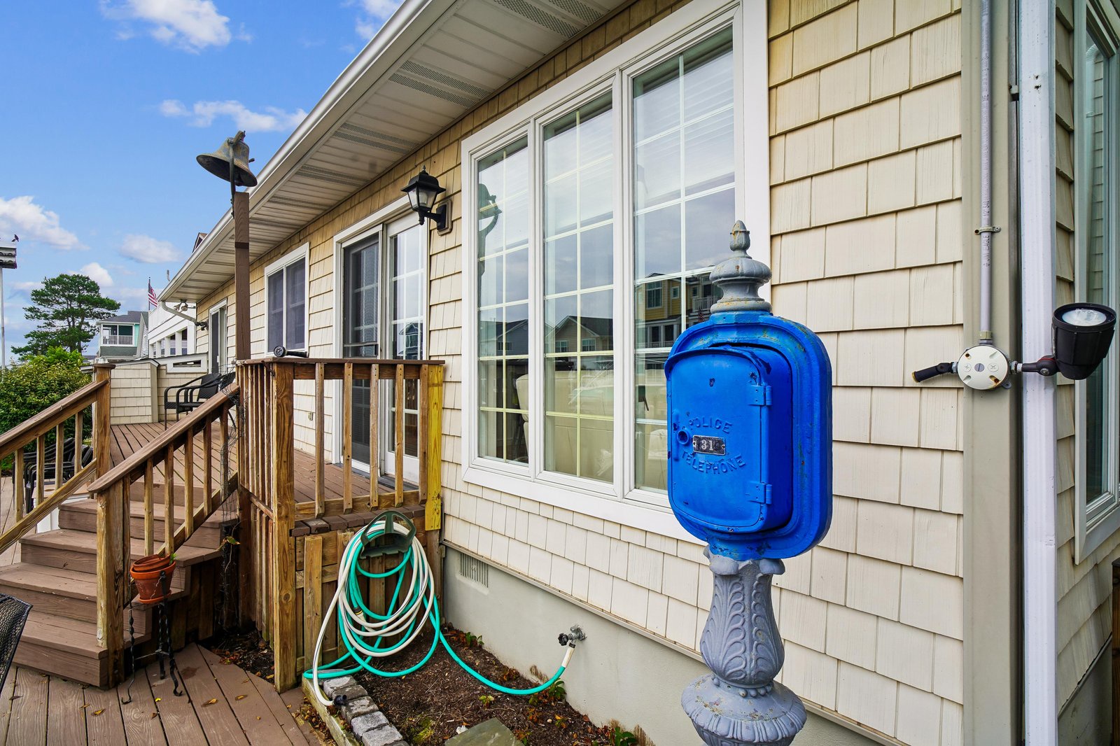 The exterior of this cozy coastal rental features classic shingled siding and a welcoming deck with stairs leading to the entrance, complete with charming nautical touches.