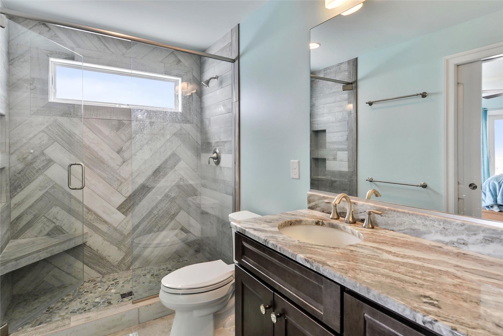 Step into your private spa-like bathroom with a stunning walk-in shower featuring elegant herringbone tile and sleek glass doors. Refresh under the rainfall showerhead after a day exploring.