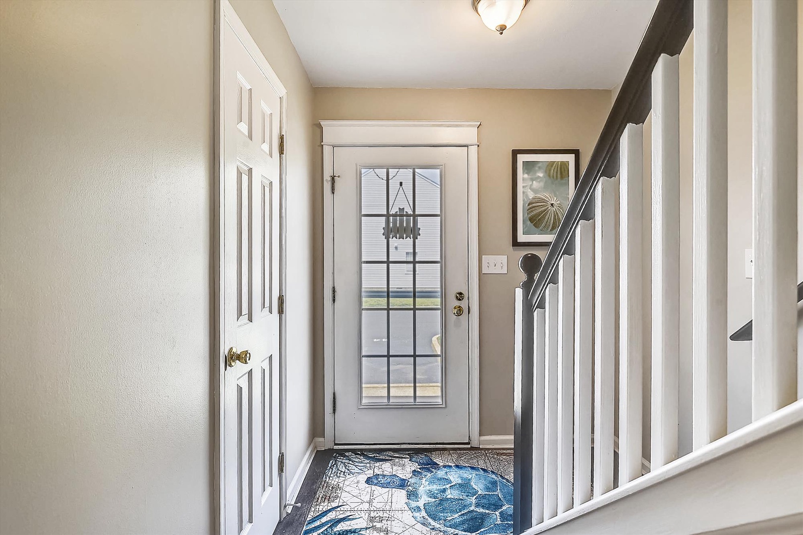 The front entrance features a bright foyer with a charming coastal-inspired rug, welcoming you into your home away from home with natural light and clean, inviting details.