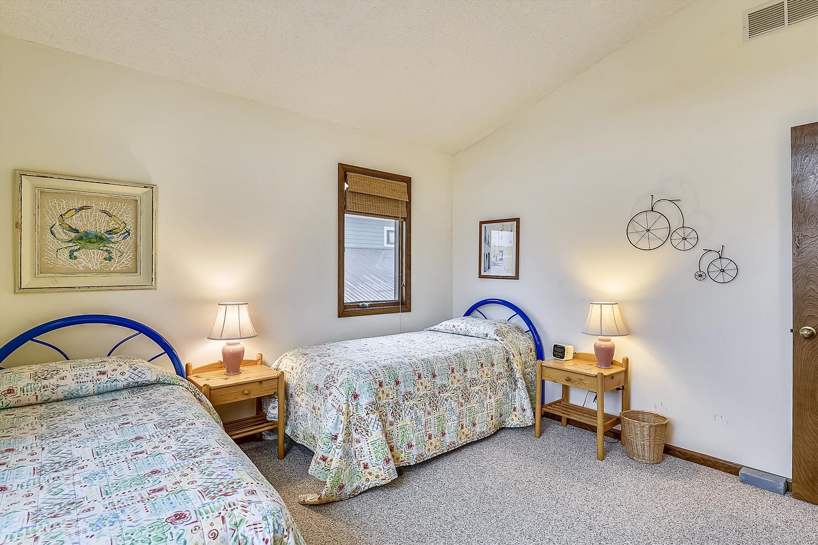 Your comfortable twin bedroom features cheerful blue bed frames, nautical artwork, and warm bedside lighting for restful nights.