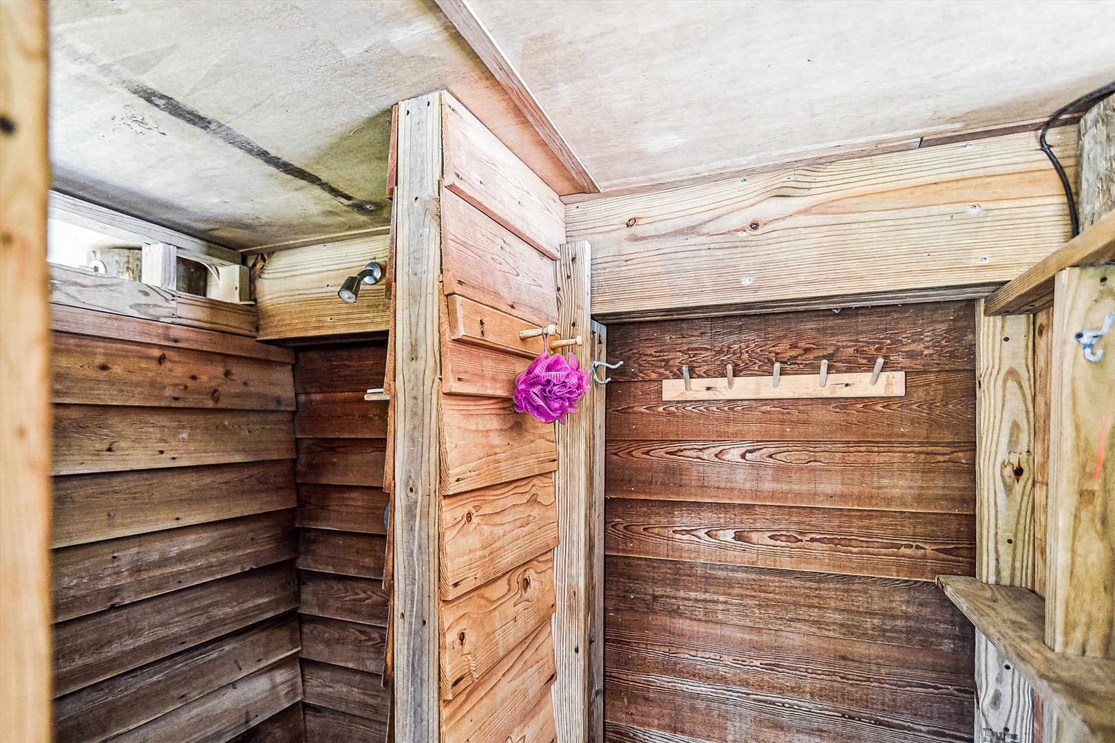 This charming wooden shower area brings rustic warmth with natural timber walls and hooks for your essentials, offering a cozy yet functional bathing space.