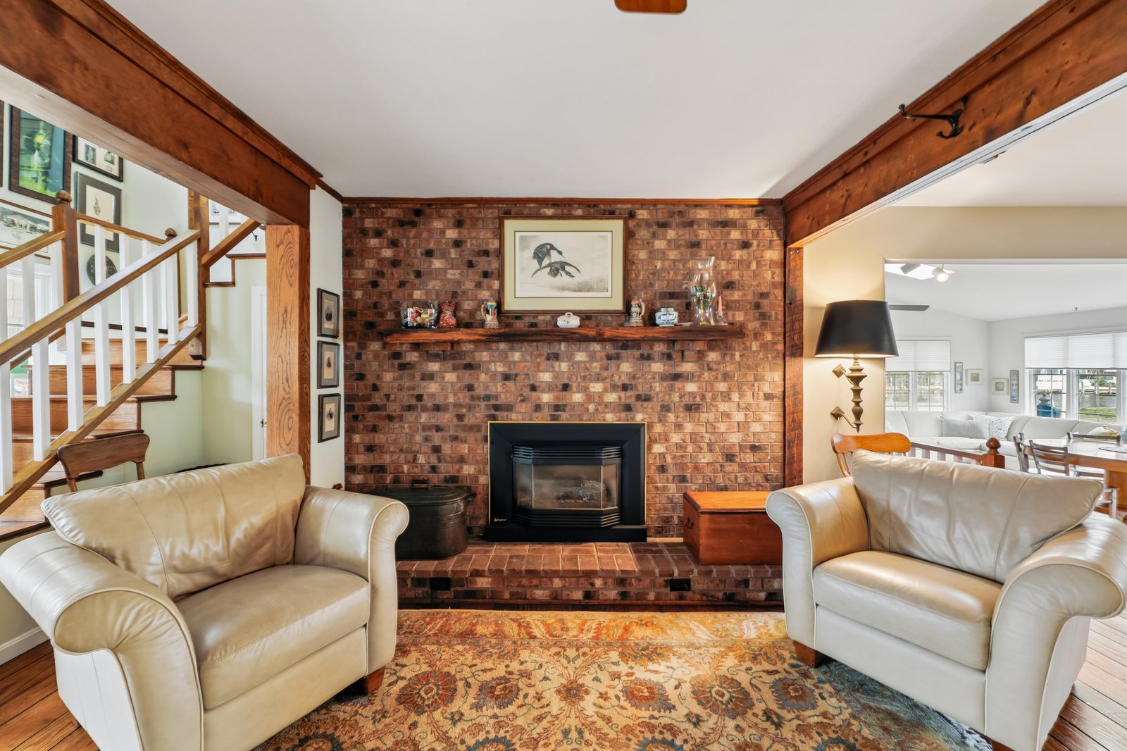 Sink into plush leather seating beside your own brick fireplace, where rustic wood beams frame a warm gathering space that feels both inviting and timelessly charming.