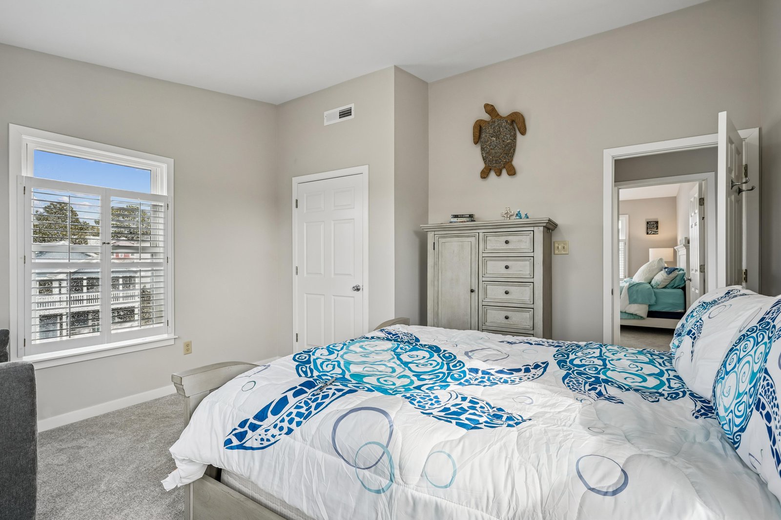 Drift off under coastal-themed bedding in your serene bedroom with charming turtle accents and views of the neighborhood. Natural light fills the space, promising peaceful mornings.
