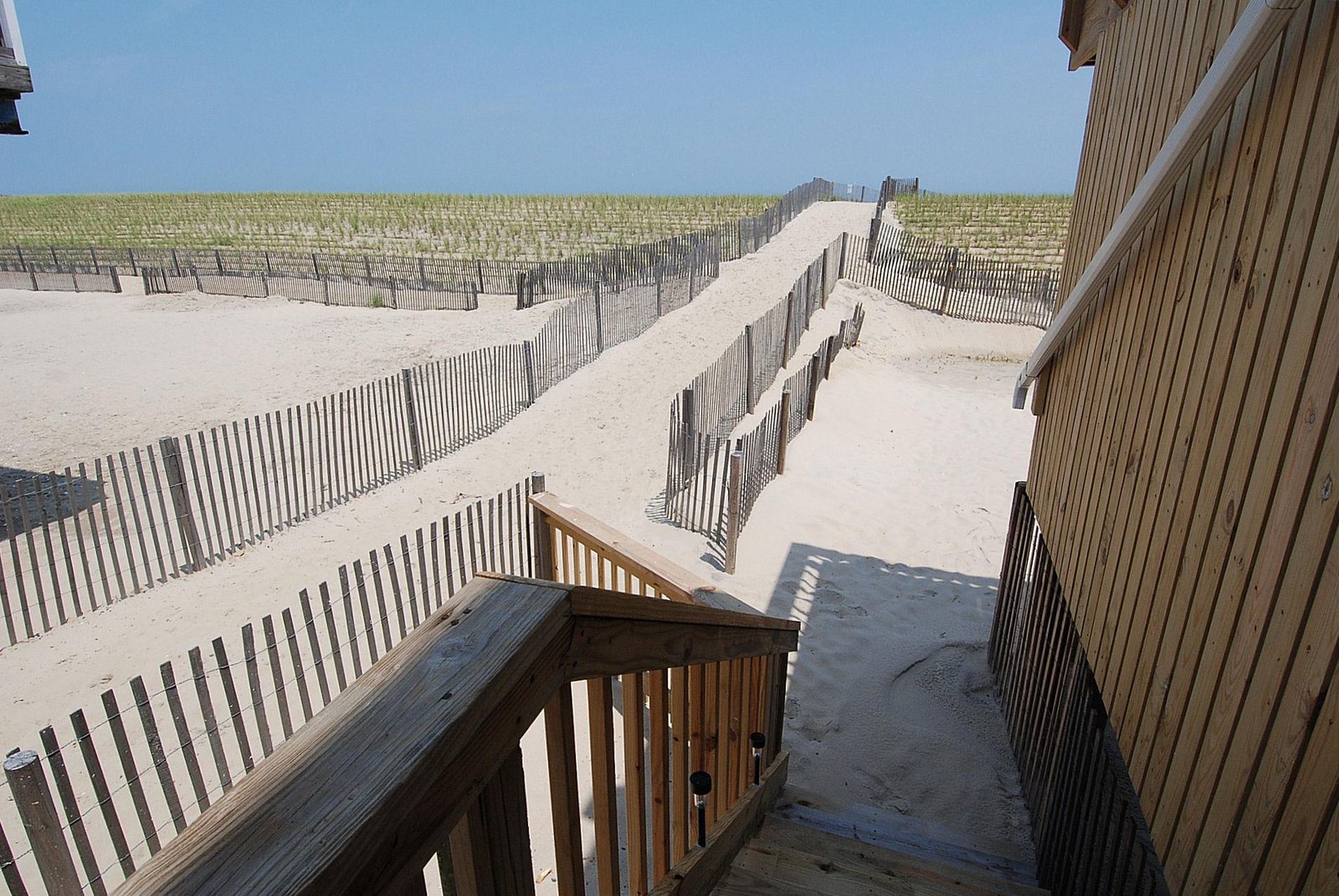 A private beachfront walkway leads from the property's entrance straight to pristine sandy shores, where dunes and gentle ocean breezes await your arrival.