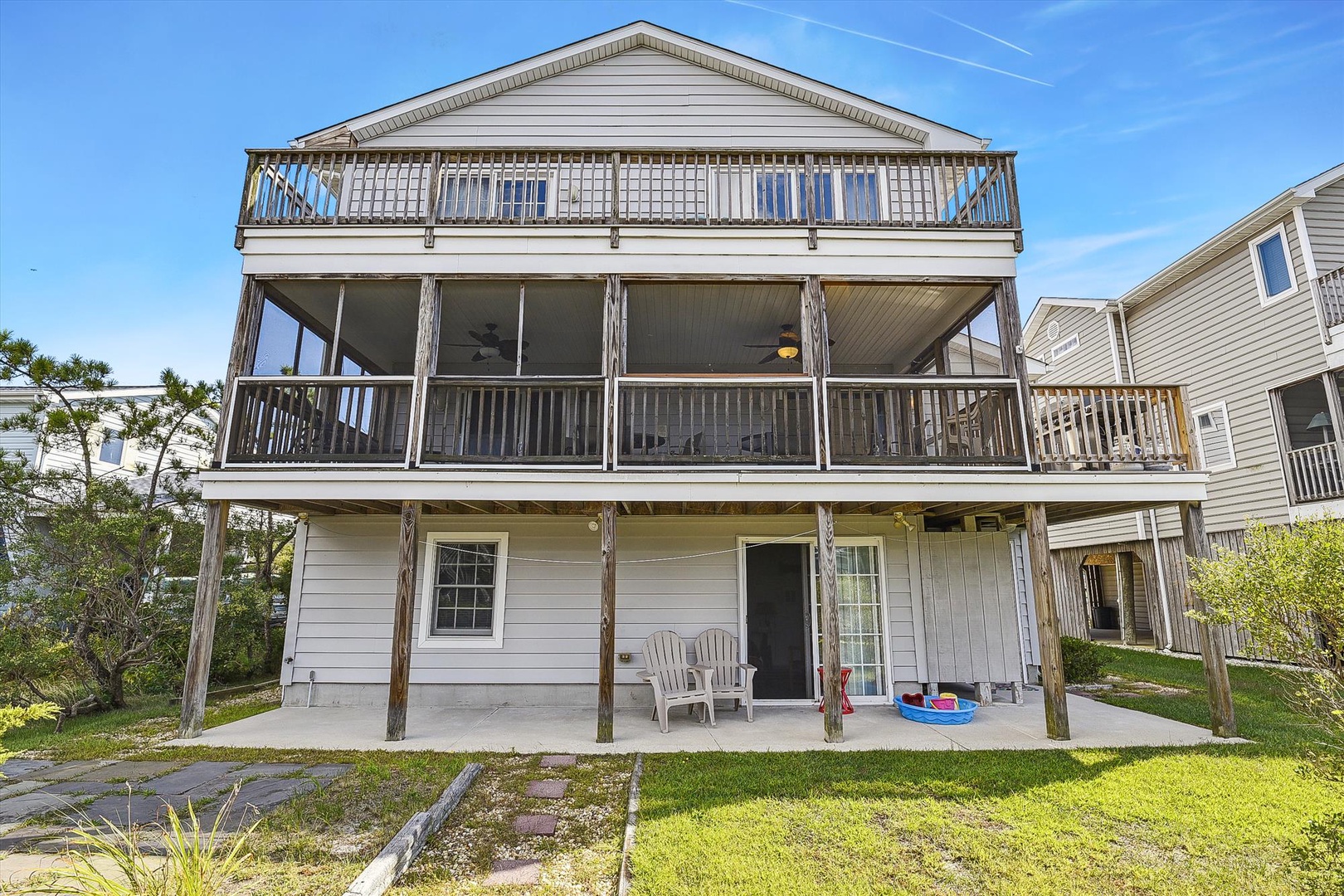 Coastal vacation home with spacious multi-level decks and screened porch, offering ample outdoor living space in a quiet neighborhood near the beach.