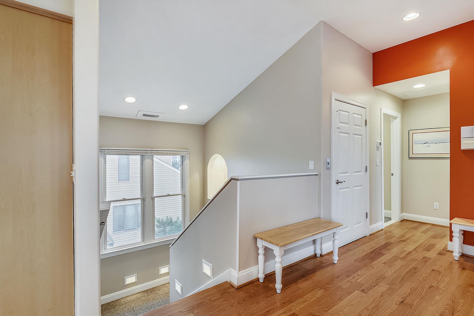 Bright upper hallway welcomes you with vaulted ceilings, warm wood floors, and a charming bench—your perfect spot to pause and settle in.