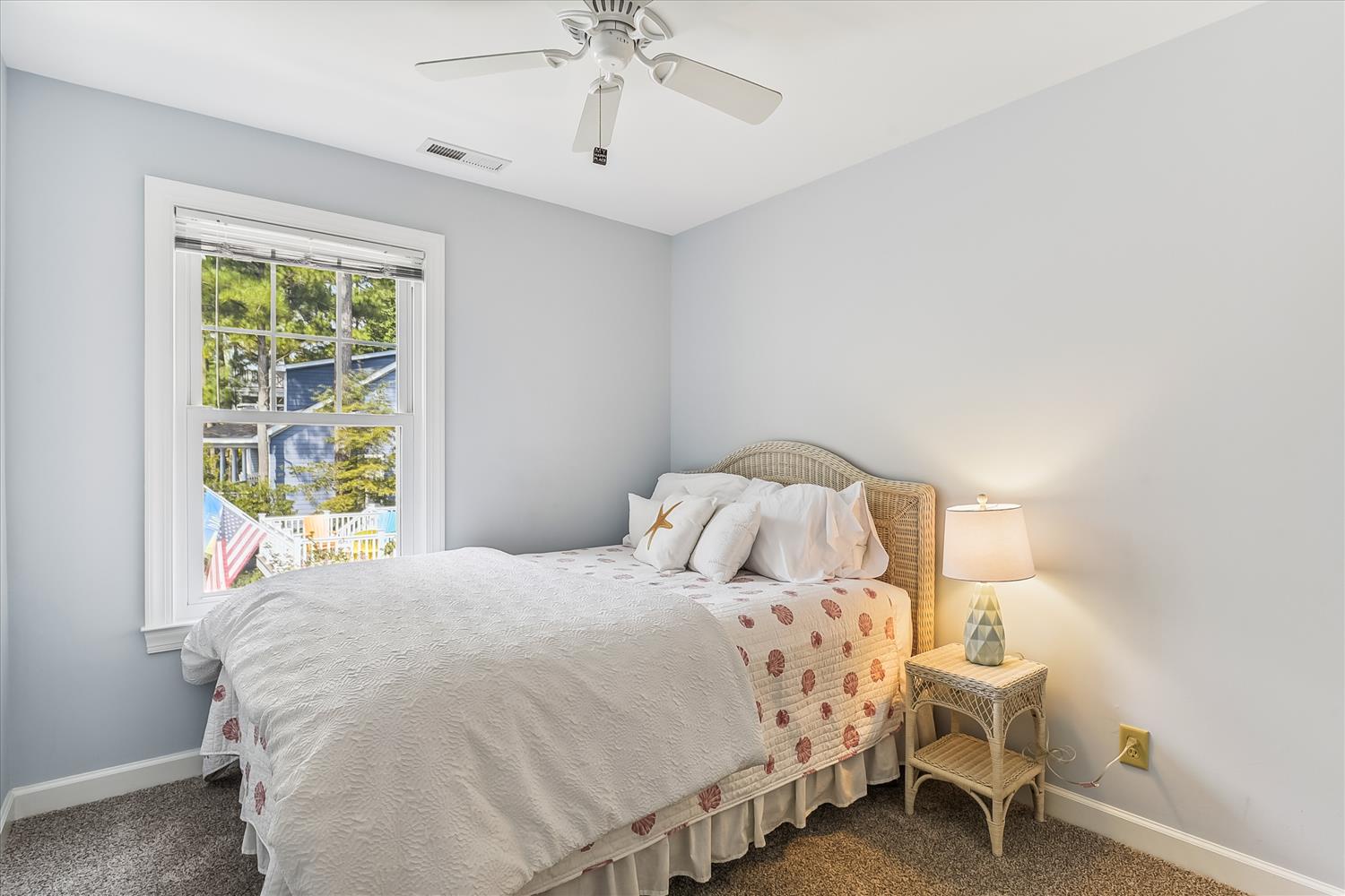 Drift off in your peaceful bedroom, where soft blue walls and a cozy bed await your arrival. The ceiling fan keeps you comfortable while sunlight filters through the window.