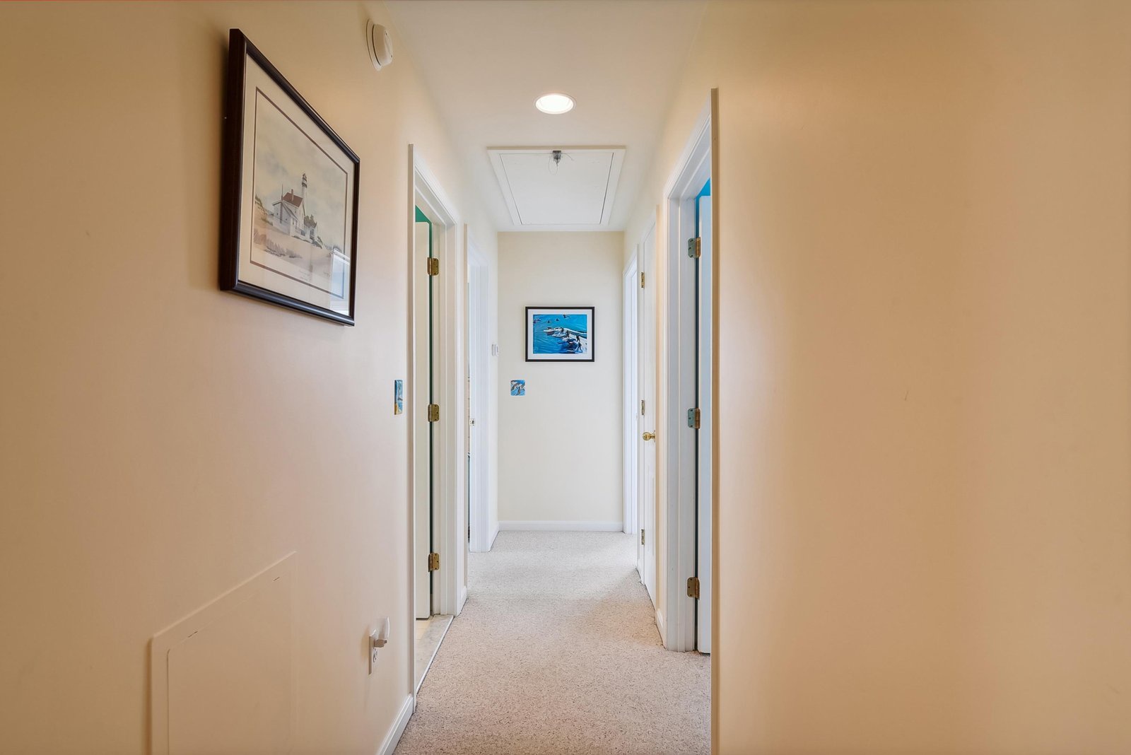 A bright, welcoming hallway guides you through your rental, with framed artwork adding character and recessed lighting creating a soft glow overhead.