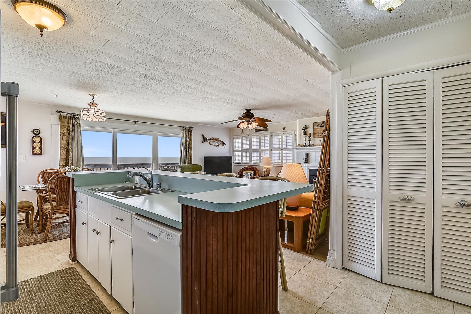 Picture yourself preparing meals in this open kitchen with coastal charm, where the island invites gathering and the expansive windows frame endless ocean views that you'll enjoy throughout your stay.