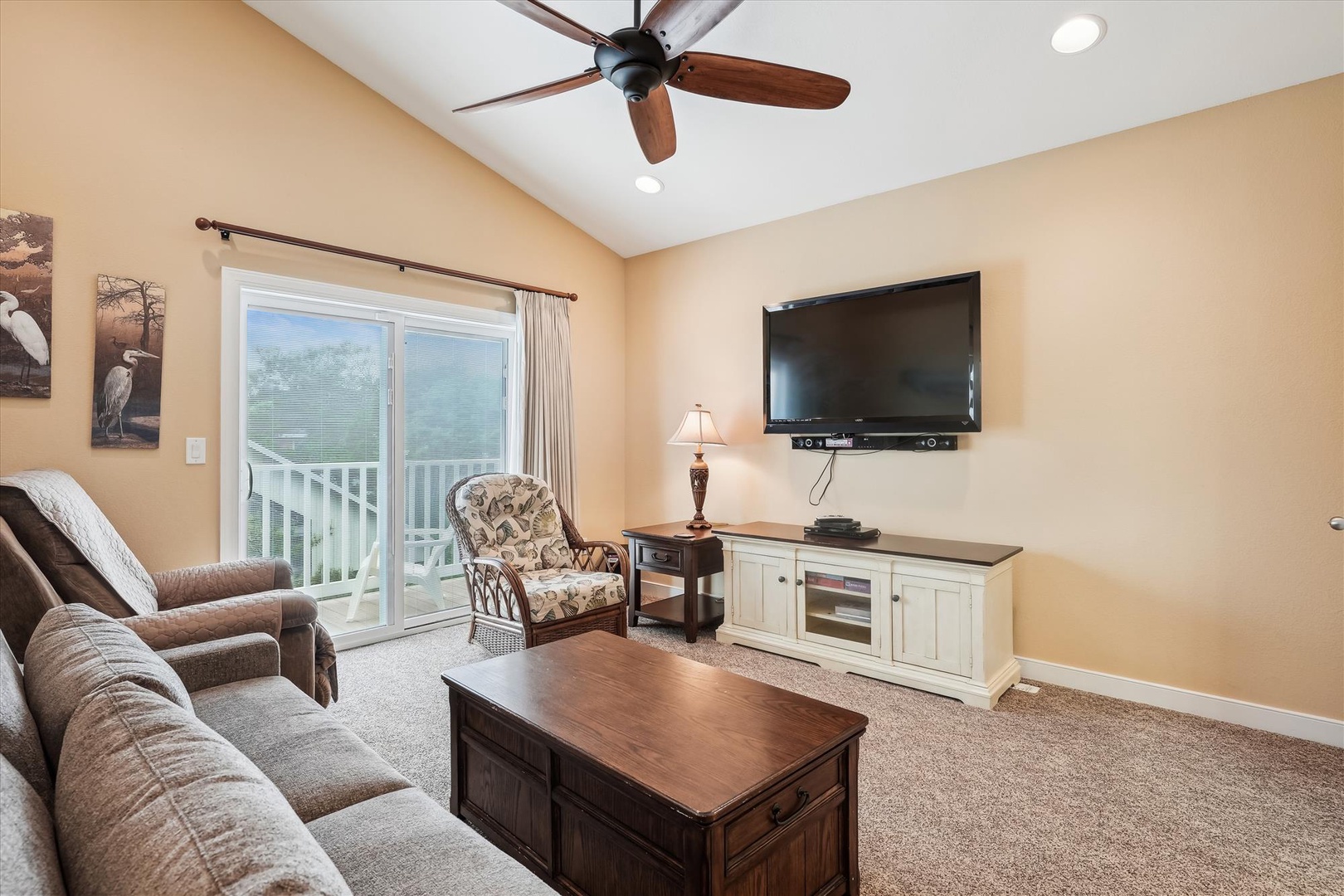 Unwind in your spacious living room with plush seating, flat-screen TV, and balcony access. The vaulted ceiling and ceiling fan create a bright, airy retreat for relaxing after your adventures.