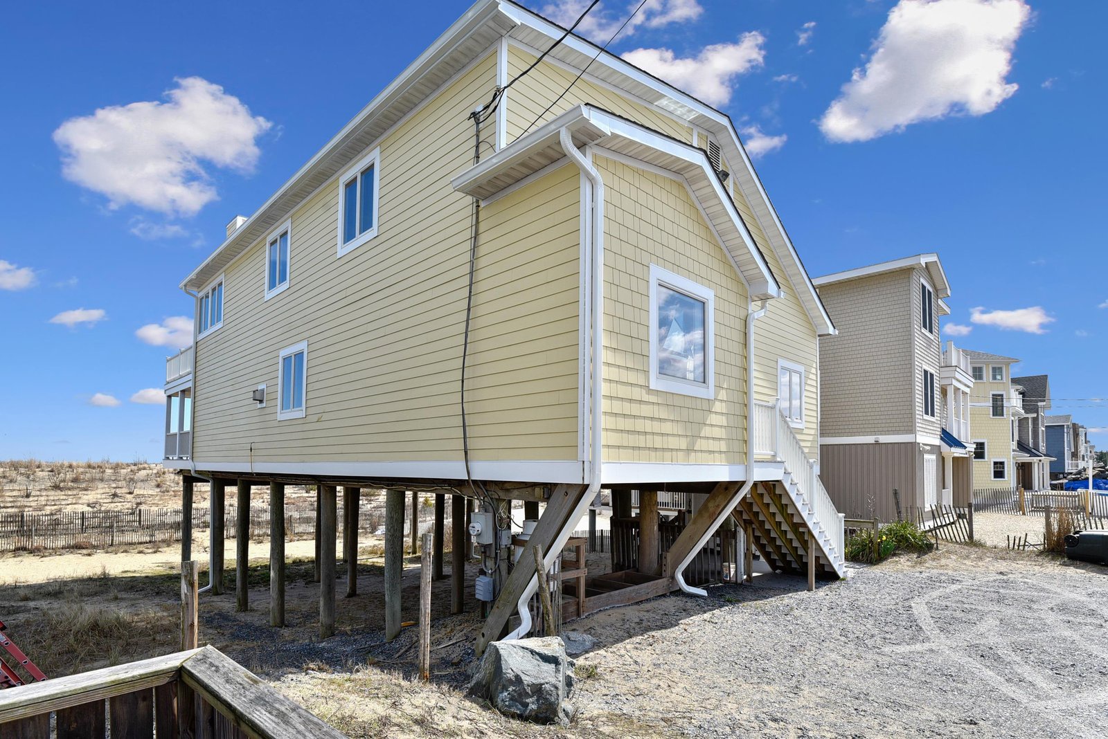 A charming beachside home elevated on stilts, offering direct access to sandy shores and coastal living in a vibrant seaside neighborhood.