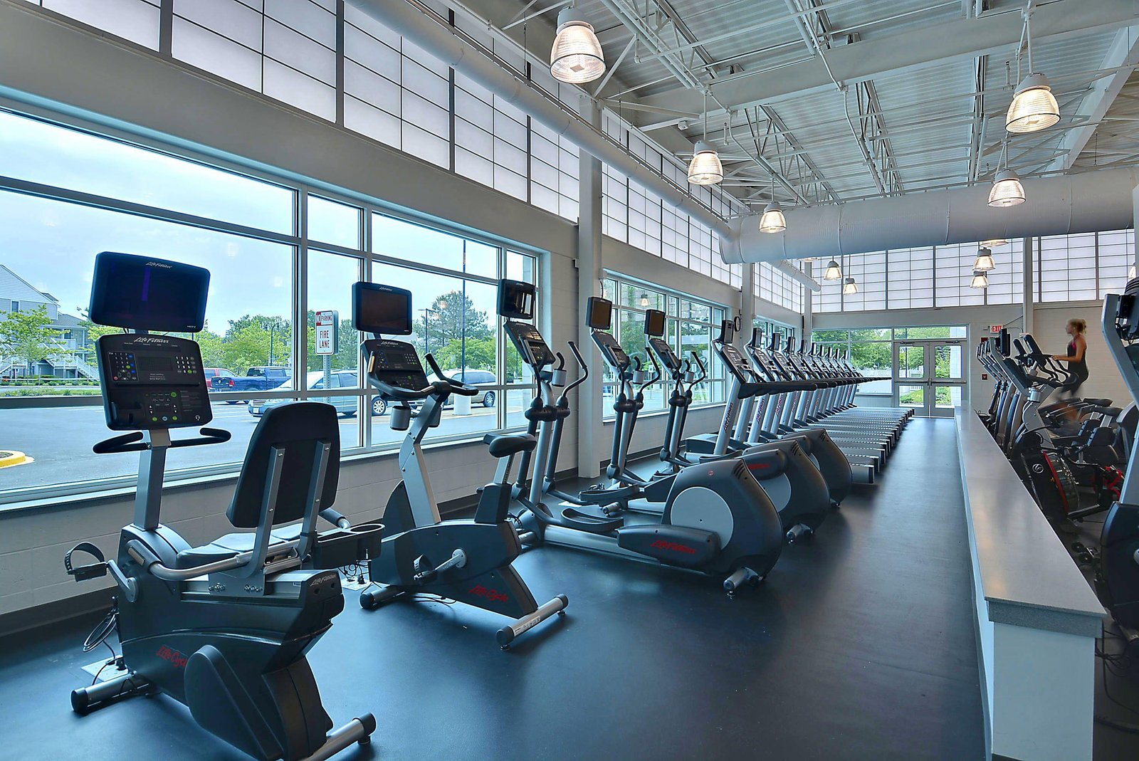 Sleek, modern fitness center with floor-to-ceiling windows and state-of-the-art cardio equipment. The bright, airy space makes every workout feel energizing and inspiring.