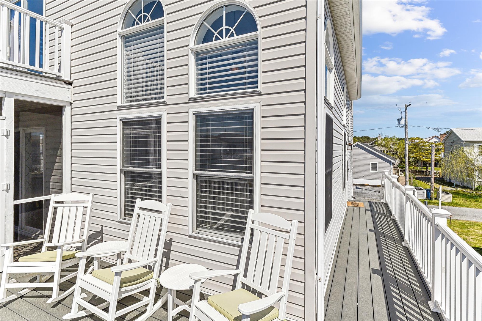 Step outside to your private balcony where classic white rocking chairs invite you to unwind with morning coffee or watch the day unfold in this peaceful neighborhood setting.