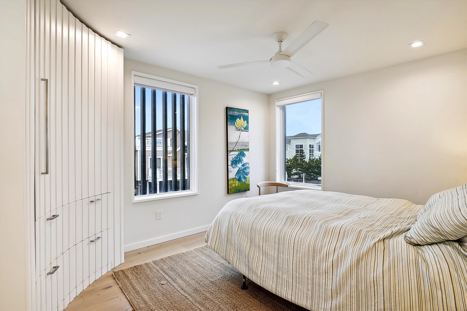 Wake up refreshed in your peaceful bedroom, with soft coastal touches and a ceiling fan keeping the space comfortable. Natural light streams through large windows, creating a bright and airy retreat.