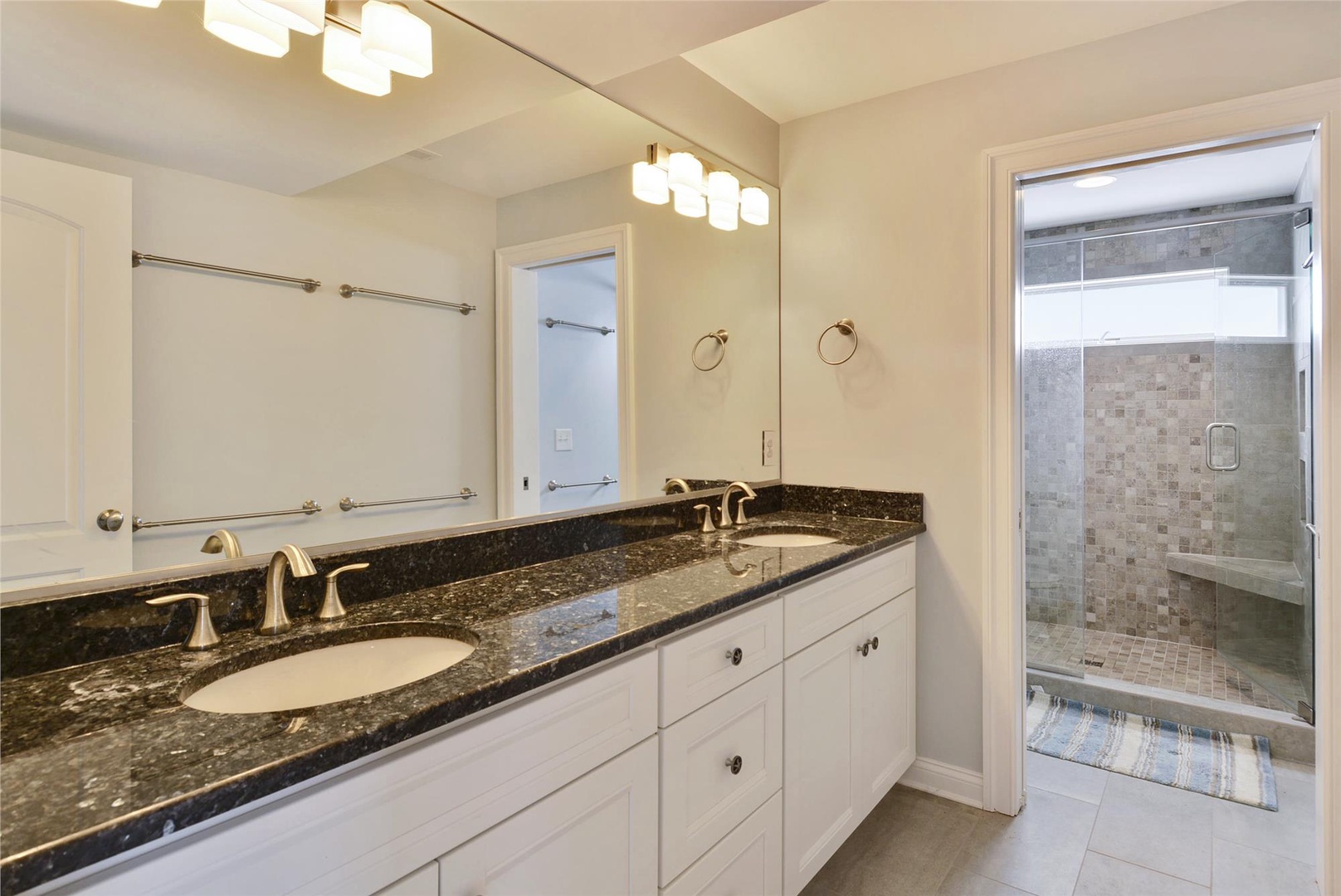 Your private ensuite bathroom features elegant dual vanities and a luxurious walk-in shower with mosaic tile accents—perfect for unwinding after a day of adventure.