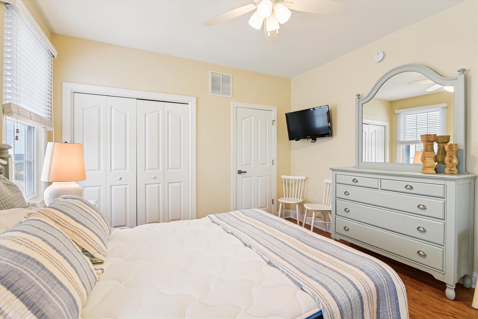 Your peaceful bedroom retreat features a plush bed, ceiling fan, wall-mounted TV, and charming coastal-inspired furnishings—perfect for unwinding after a day of adventure.