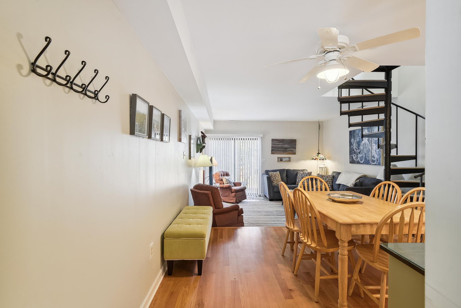 Step into your open-concept living and dining space, where soaring ceilings and warm wood floors welcome you home. Gather around the dining table, relax in cozy seating areas, and let the ceiling fan keep you comfortable throughout your stay.