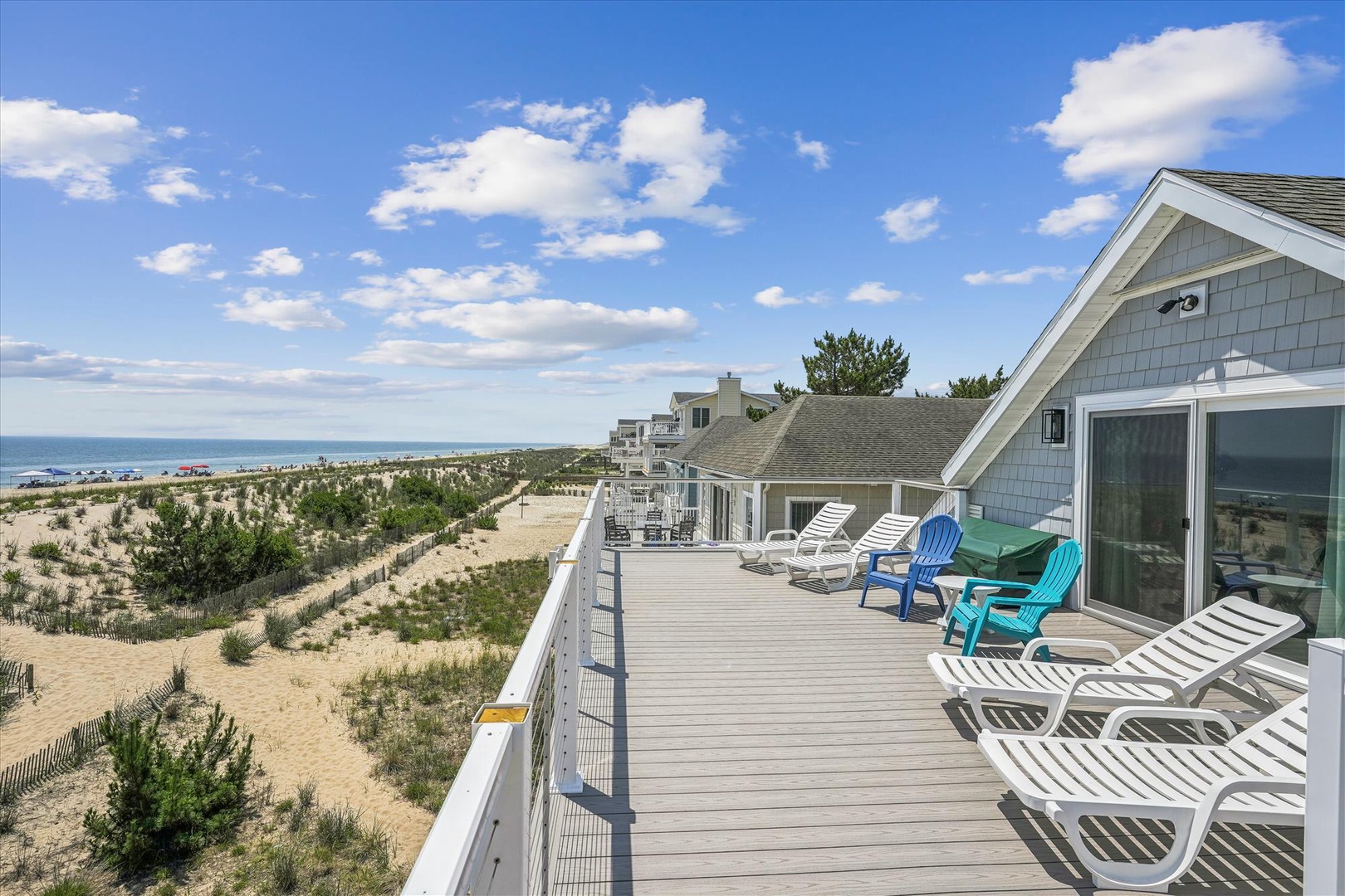 This beachfront property features a spacious deck with comfortable lounge seating, offering direct access to pristine sandy shores and stunning ocean panoramas.