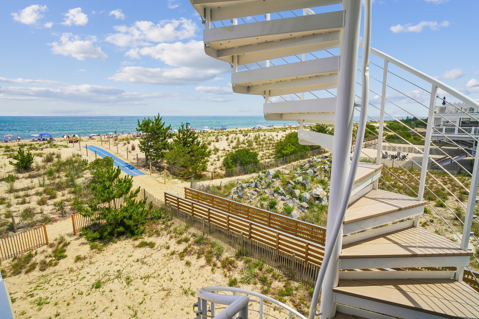 This spiral staircase leads directly from your deck to sun-soaked sands and sparkling water, putting beach days at your doorstep. The view captures coastal dunes and open horizons, perfect for a seaside escape.