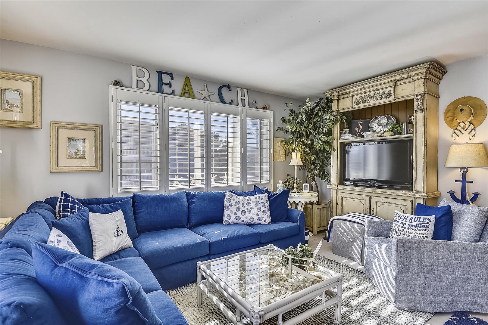 Settle into this bright coastal living room, where plush navy seating and beach-inspired décor create a cheerful retreat for unwinding after your day exploring the shore.