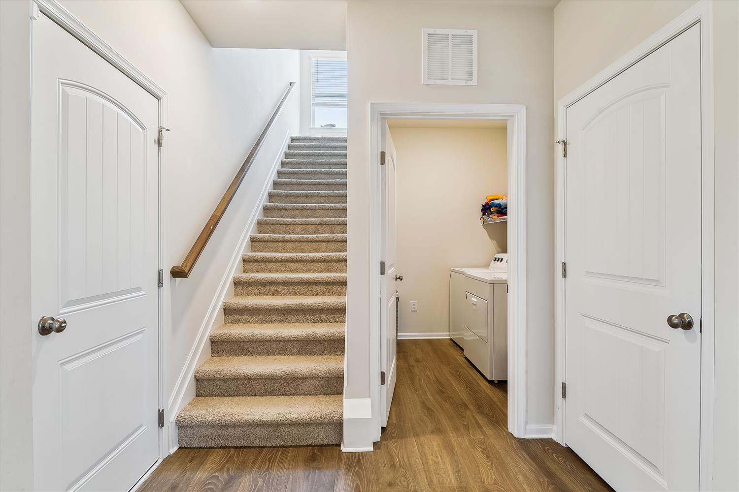 A bright, welcoming entry hall with stylish carpeted stairs leading to your upstairs spaces and convenient storage or laundry access just steps away.