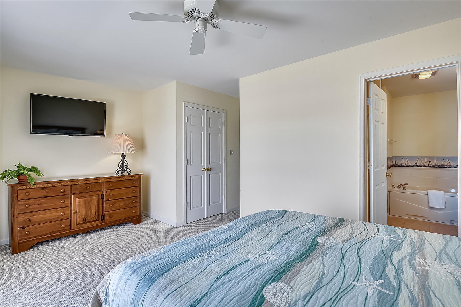 Relax in your spacious bedroom with soft coastal bedding, ceiling fan, TV for your favorite shows, and an en-suite bath for your convenience.