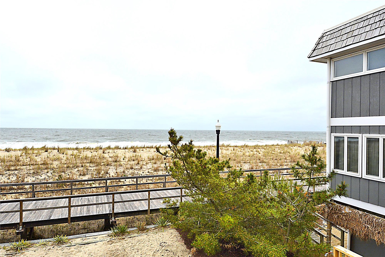 Beachfront property with stunning ocean views and direct beach access via wooden walkway.