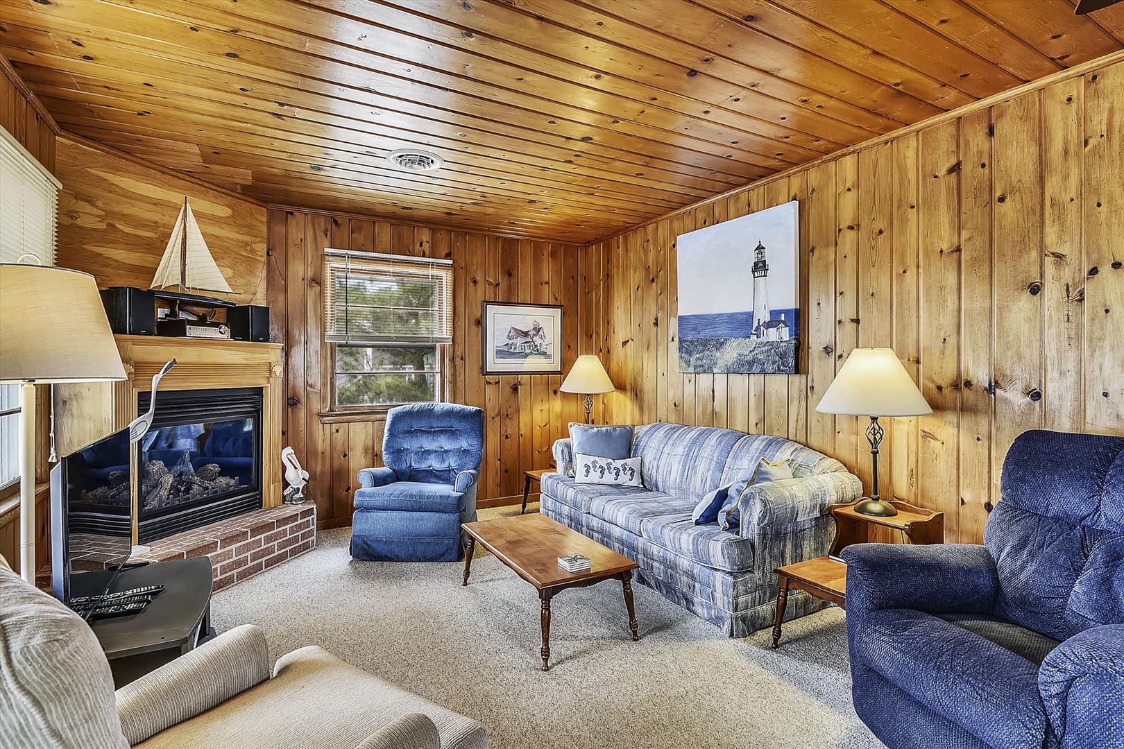 Sink into the plush seating and let the warmth of the gas fireplace embrace you in this cozy wood-paneled living room, where coastal charm meets comfort.