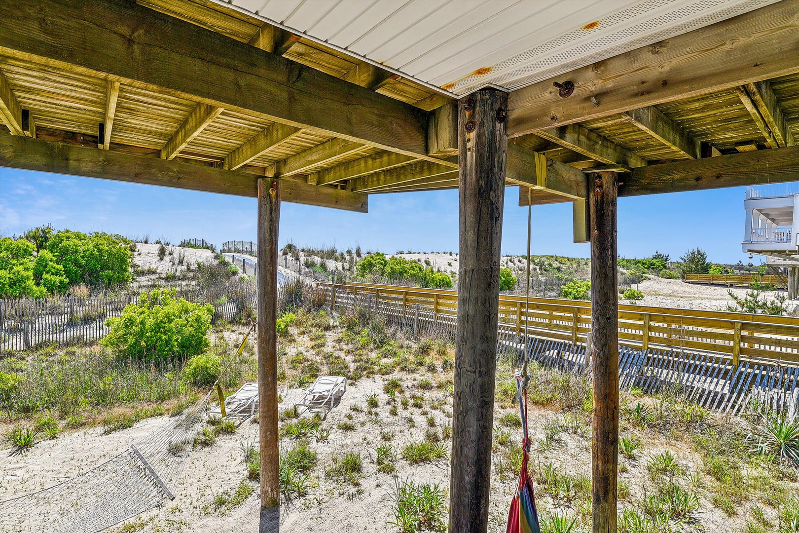 Coastal retreat featuring a covered deck with dunes, native beach grasses, and easy access to outdoor relaxation just steps from the shore.