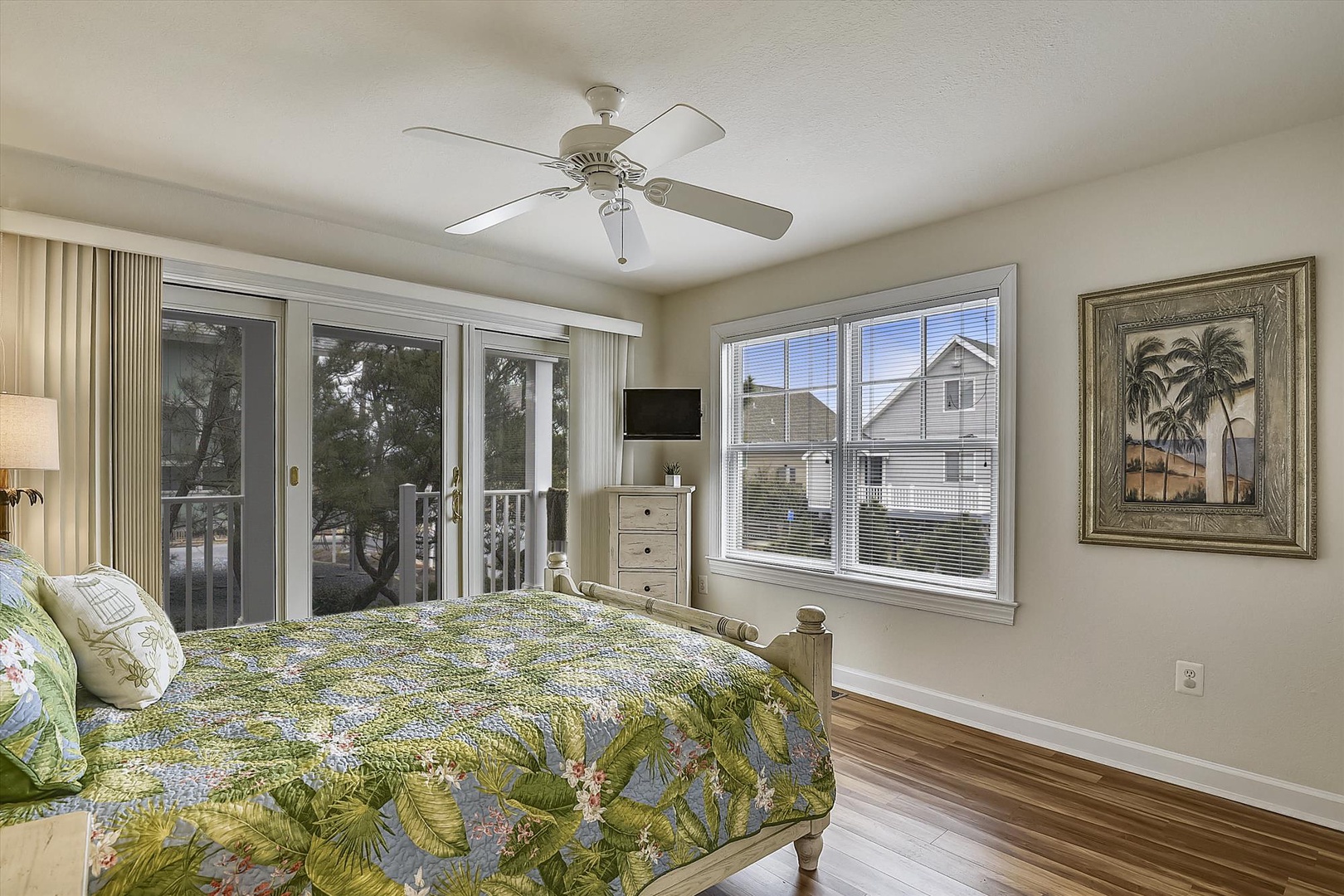 Wake up in your tropical-themed bedroom with views of the neighborhood through bright windows and a private balcony access.